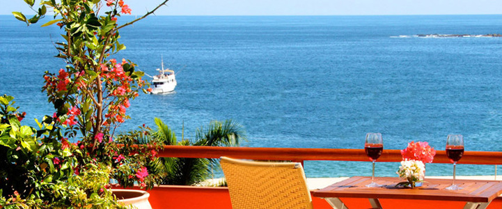 A comfortable chair, table and glass of wine look out to the bays of Huatulco, Mexico.
